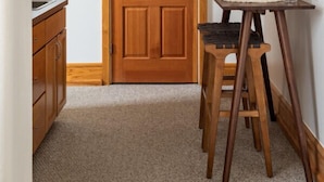 A hallway with a wooden door, a small table with a chair, and framed pictures on the wall. - Historic Hearth · Newly Redesigned Condo in Historic Building (Traverse City)