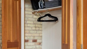 A room with a wooden wardrobe, a brick wall, and a small table with a stroller. - Historic Hearth · Newly Redesigned Condo in Historic Building (Traverse City)