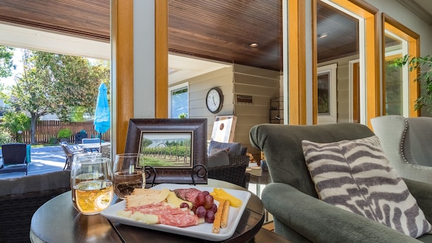 A dining table with a plate of assorted meats, cheeses, and fruits, and two glasses of beer. - HEATED Pool & Hot Tub in a Quiet Neighborhood- Walk to Town- Dog Friendly (Walla Walla)