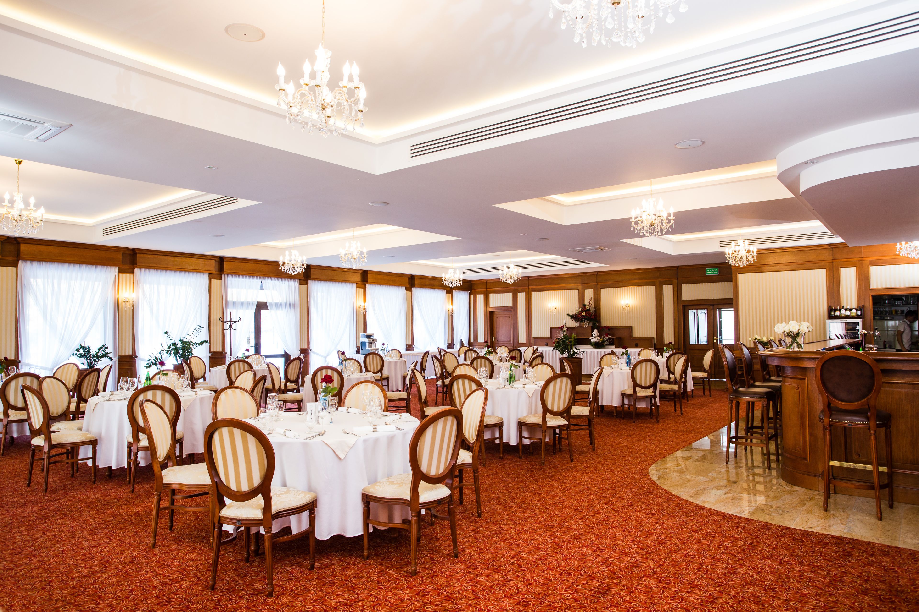 Un salón de banquetes con mesas redondas, sillas, candelabros y una zona de bar.