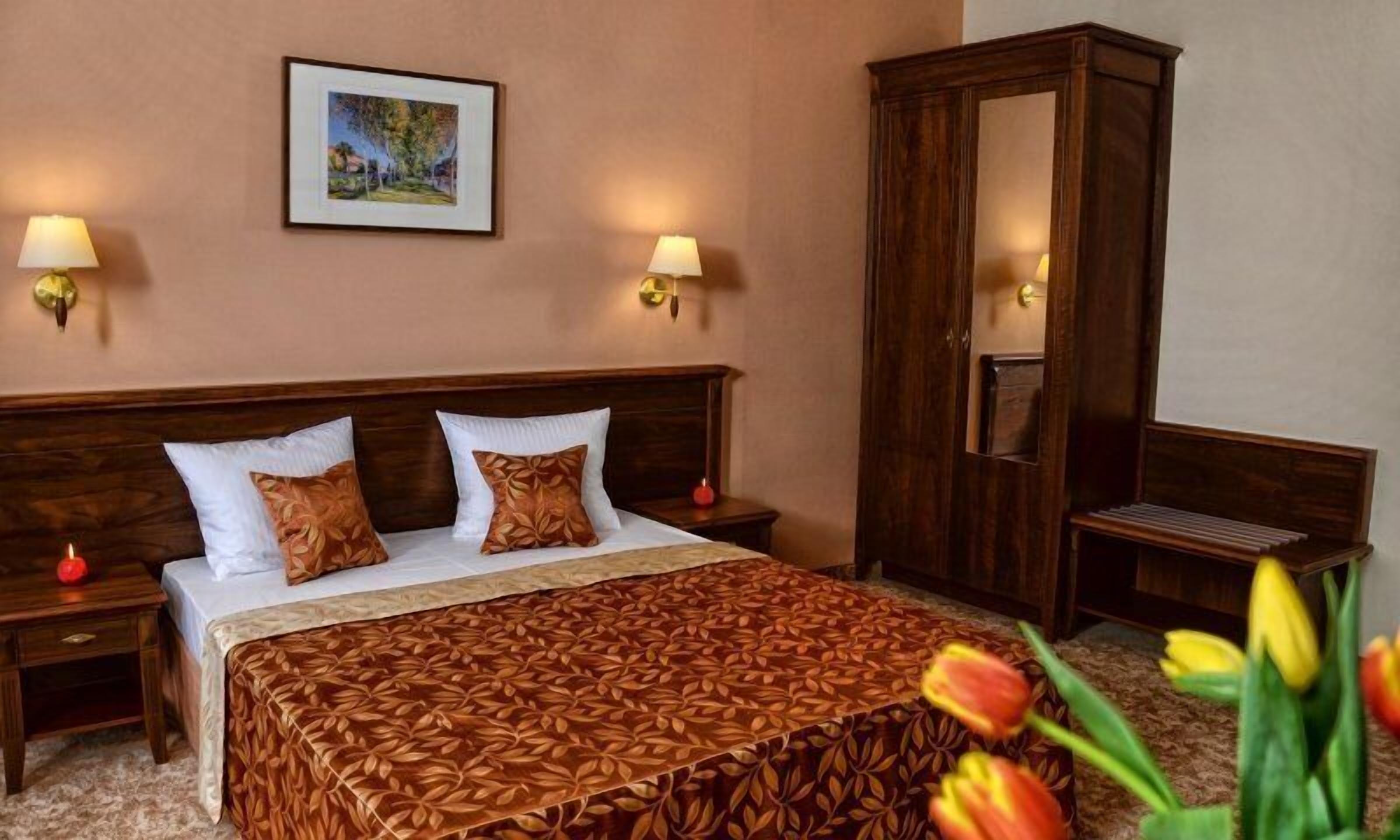 A hotel room with a large bed, two nightstands, a wardrobe, and a framed picture on the wall.