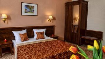 A hotel room with a large bed, two nightstands, a wardrobe, and a framed picture on the wall.