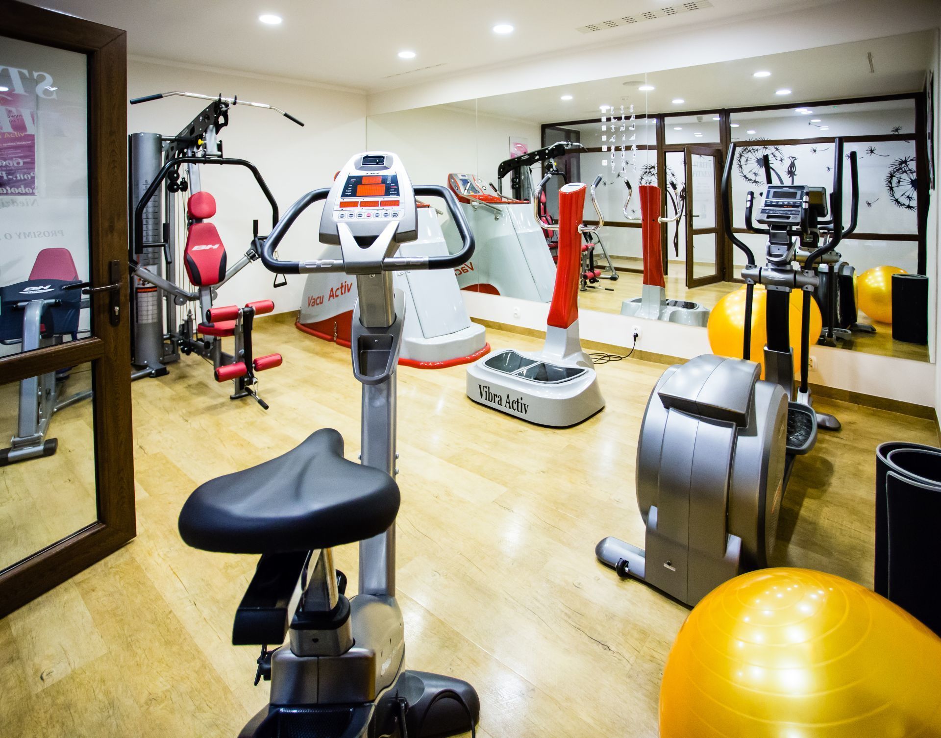 Een sportschool met diverse fitnessapparaten, waaronder loopbanden, hometrainers en krachtapparaten.