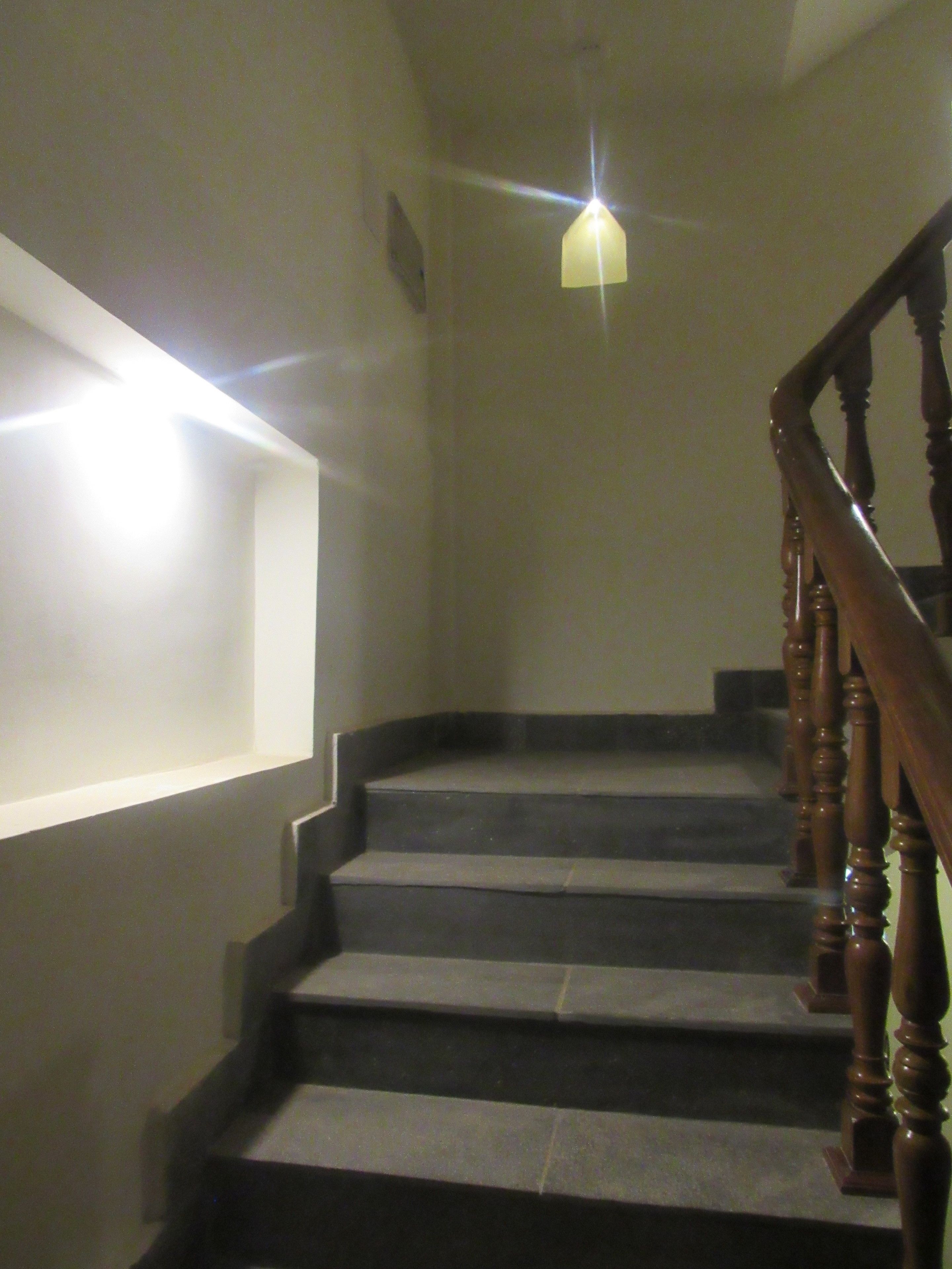 Una escalera con barandillas de madera y una lámpara colgante.