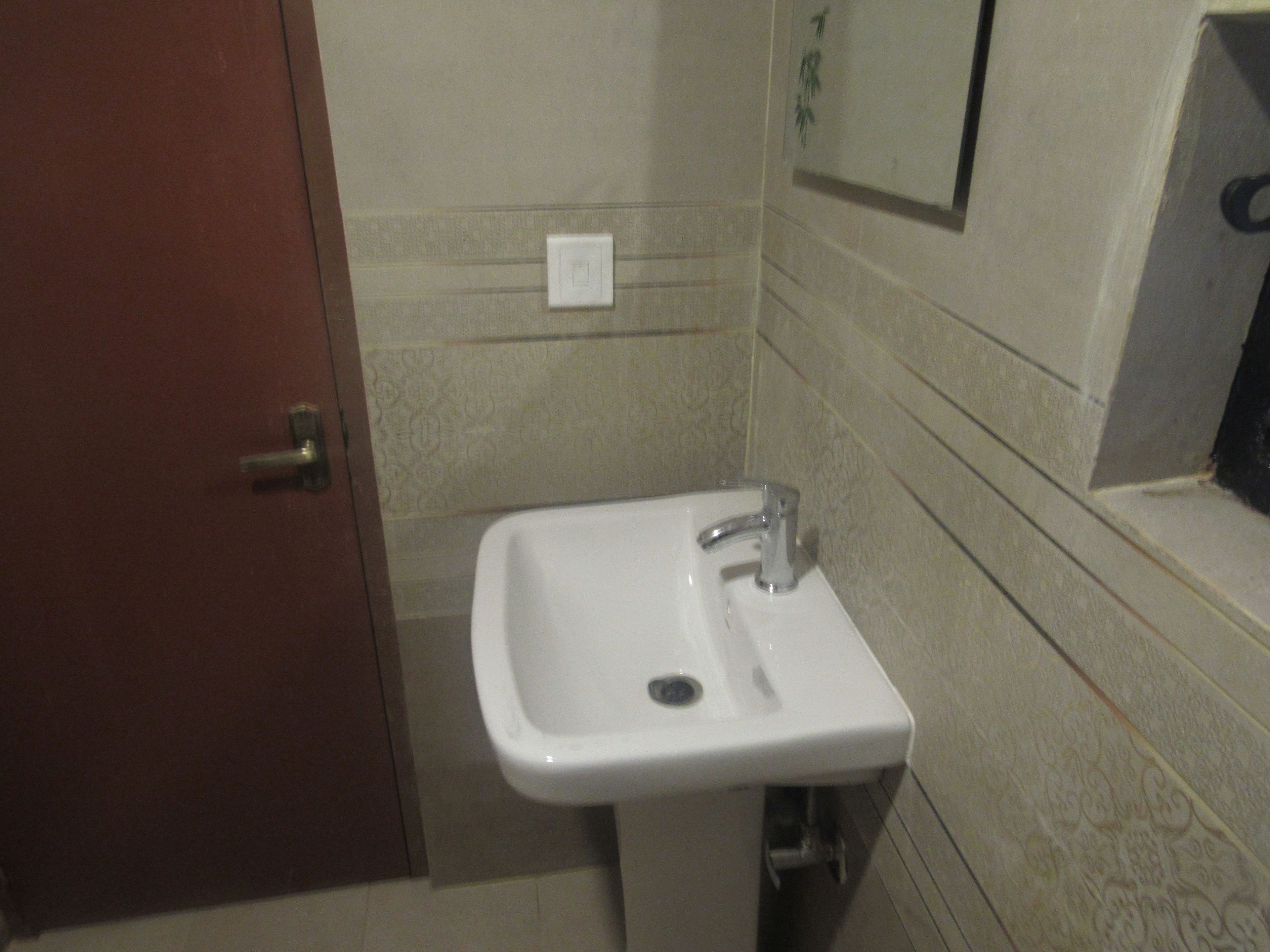 Un baño con un lavabo blanco, un espejo y una puerta.