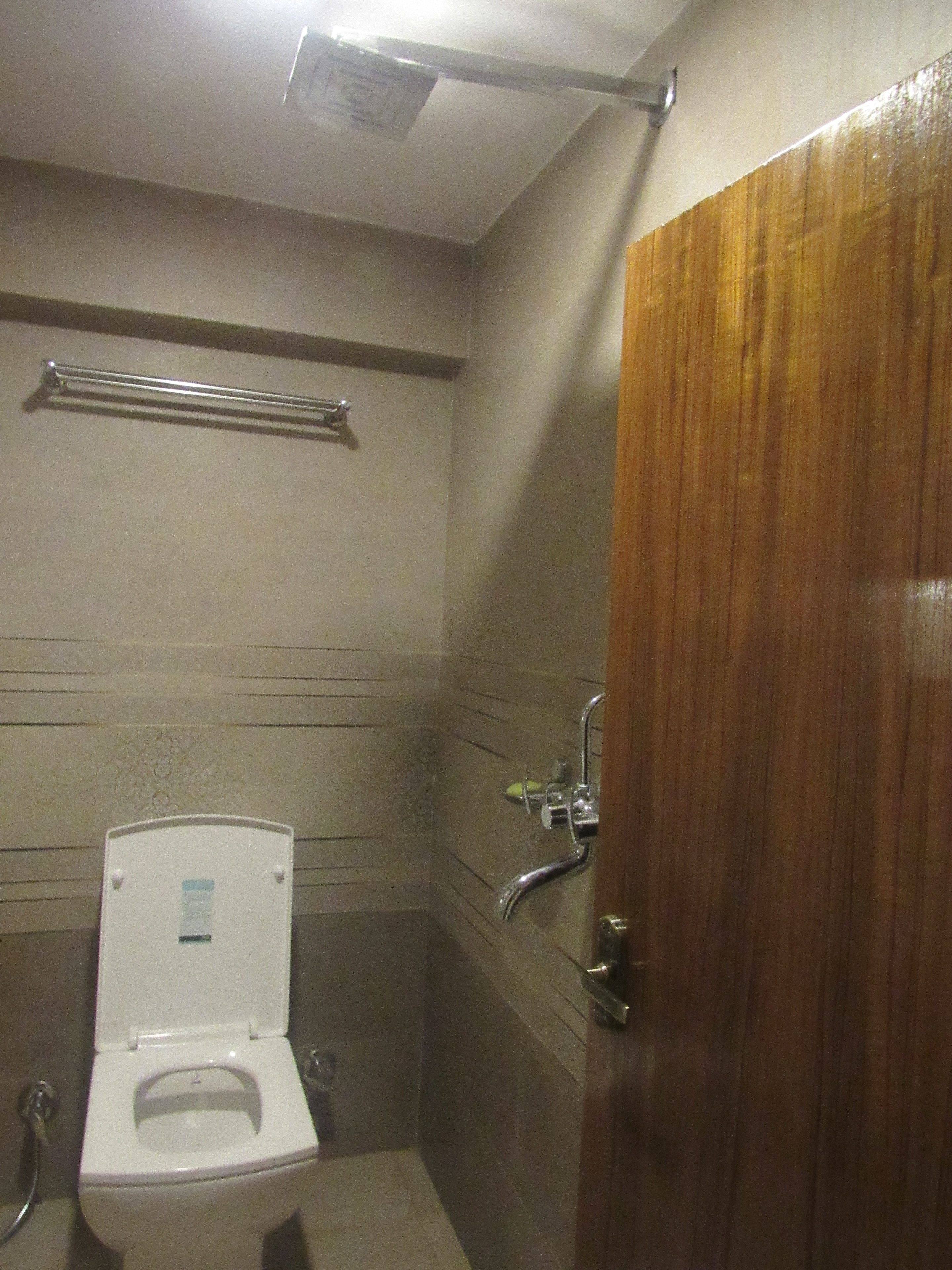 Un baño pequeño y funcional con inodoro, secamanos y barra para toallas.