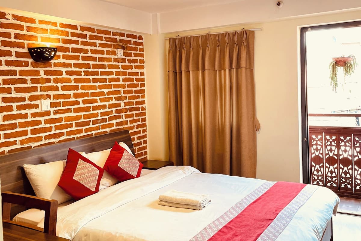 A neatly made bed with a red and white bedspread, a wooden headboard, and a brick-patterned wall.