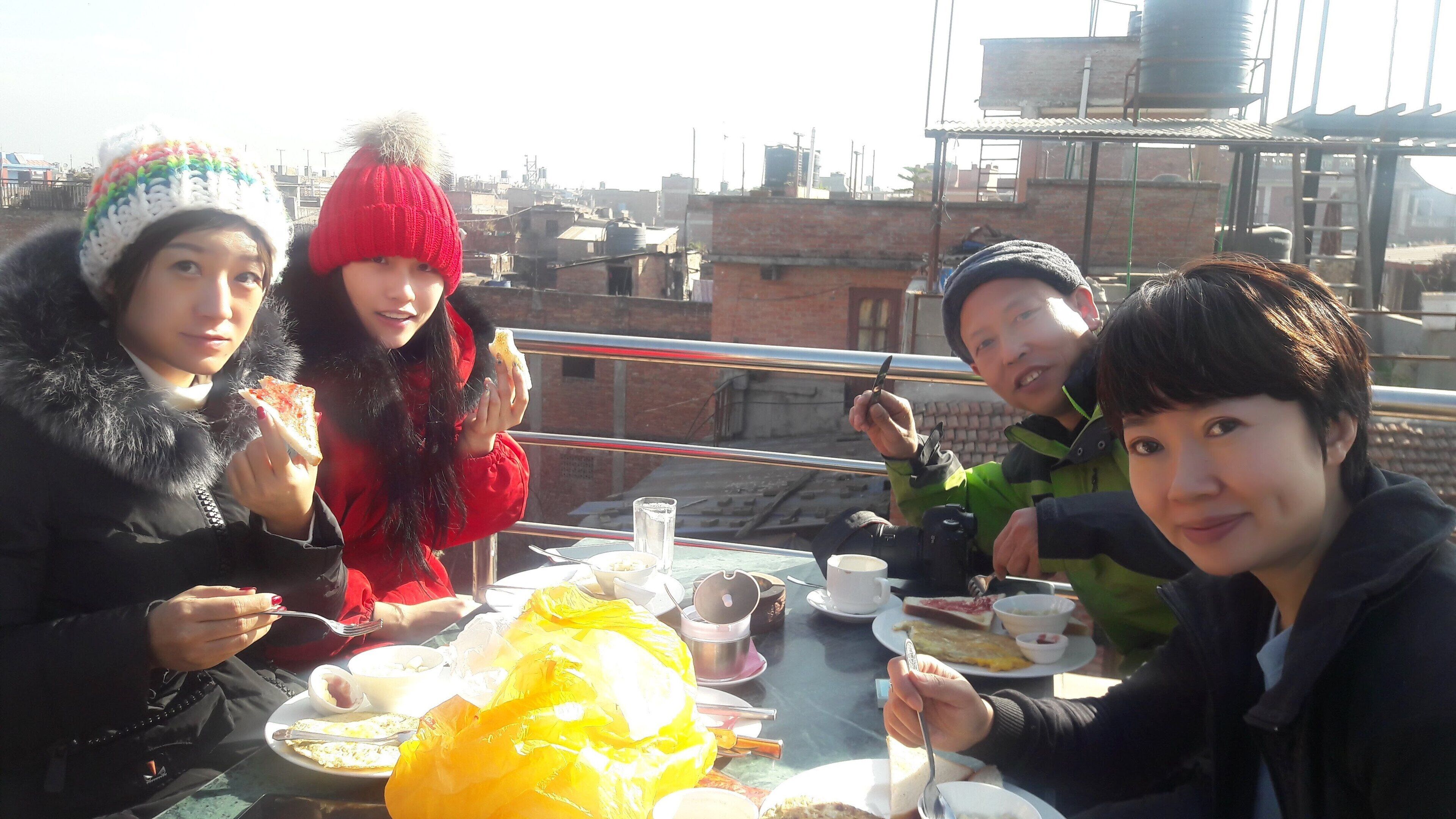 Un grupo de personas cenando al aire libre con un paisaje urbano de fondo.