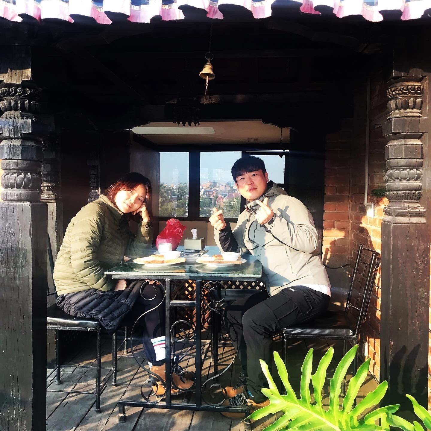 Duas pessoas jantando em mesa ao ar livre, com vista para a cidade.