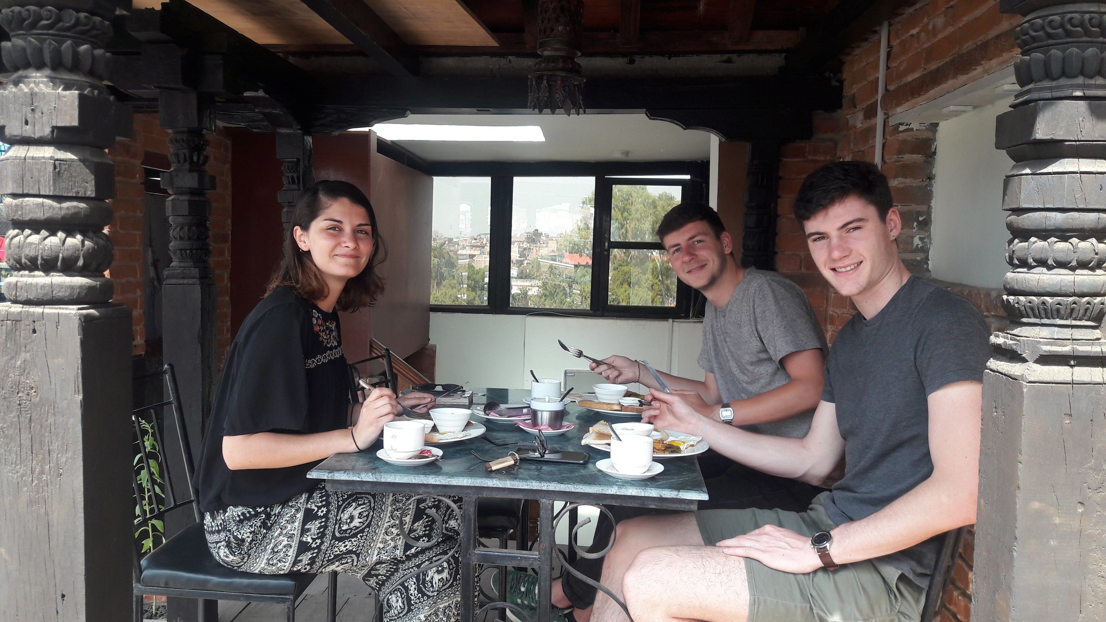 A group of people dining at a table with a view of the city through a window.