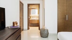 A modern hotel room with a wooden wardrobe, a television on a wooden stand, and a bathroom visible through an open door. - Fantastay - Portokal Downtown Dubai (Dubai)