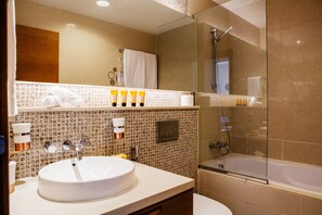 A modern bathroom with a round sink, a glass-enclosed shower, and a tiled backsplash.