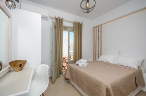 Ein Hotelzimmer mit Bett, Schreibtisch und Stuhl. Ein Fenster mit Vorhängen, eine Tür und ein Blick ins Freie.