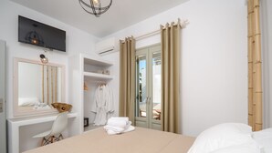 Habitació d'hotel amb un llit, una tocador amb mirall, una televisió i un armari.