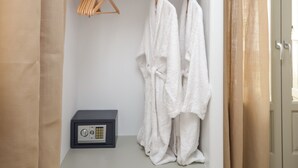 Un armari blanc amb un televisor a dalt, una caixa forta i abrics penjats.