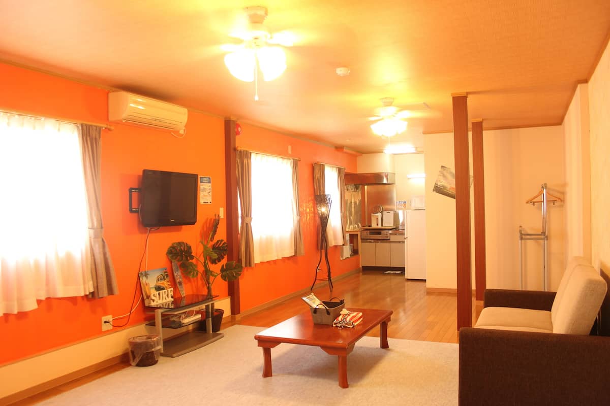 A living room with orange walls, a wooden coffee table, a sofa, and a television.
