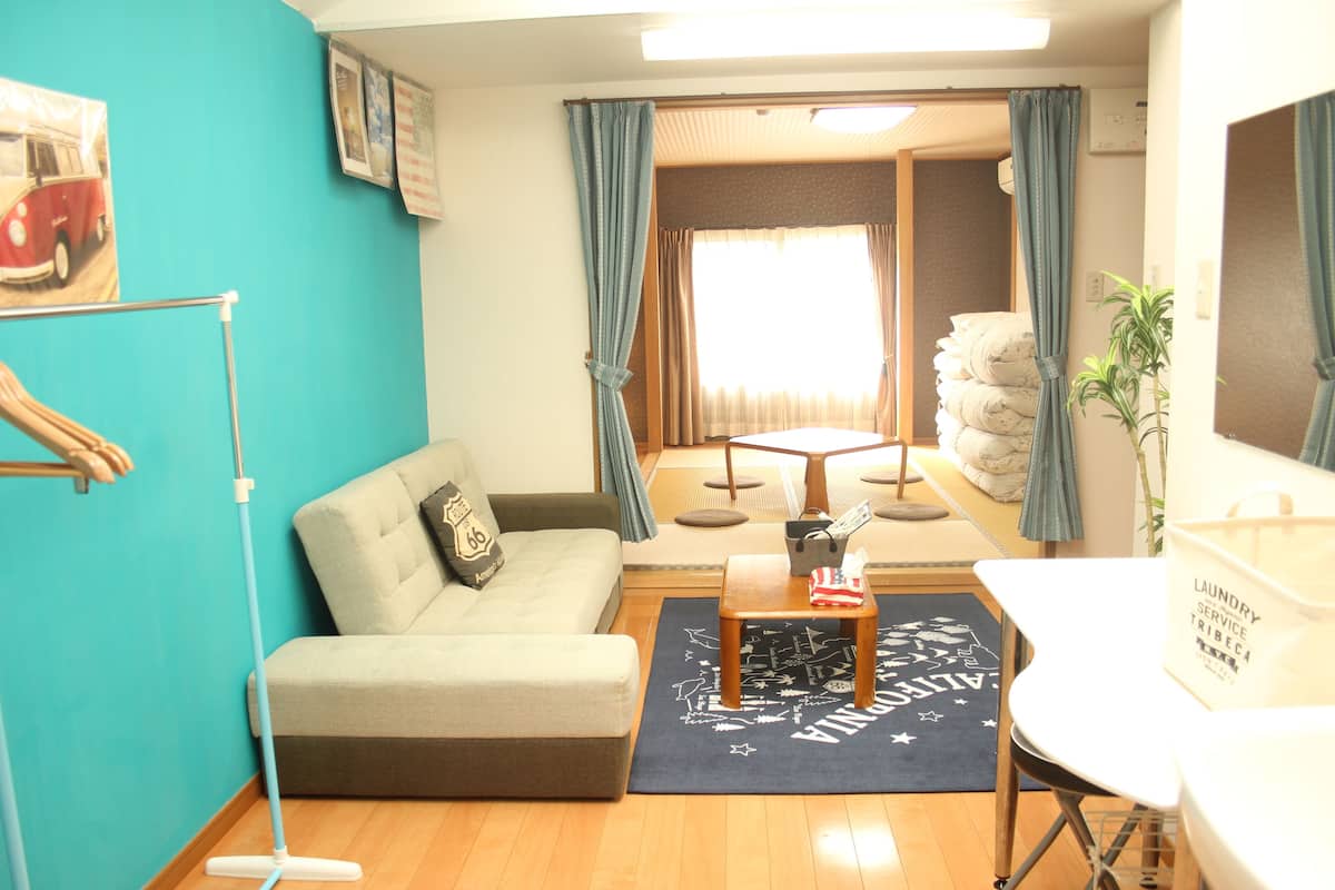 A living room with a sofa, a coffee table, a dining table, and a laundry service sign.