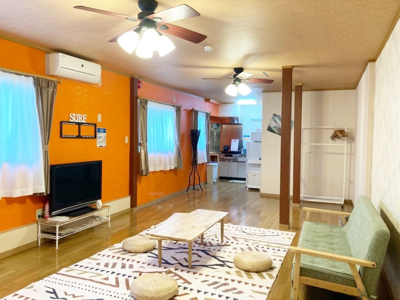 A living room with a television, a table, a sofa, and a ceiling fan.