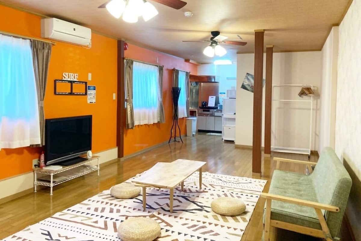 A living room with a television, a table, a sofa, and a ceiling fan.