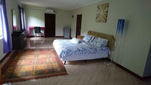 A bedroom with a bed, a rug, a dresser, and a door. - Royale Panorama View Apartment (Mahé Island)