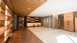 Eine moderne Lobby mit Holzvertäfelung, einem Empfangstresen und einer Marmorwand.