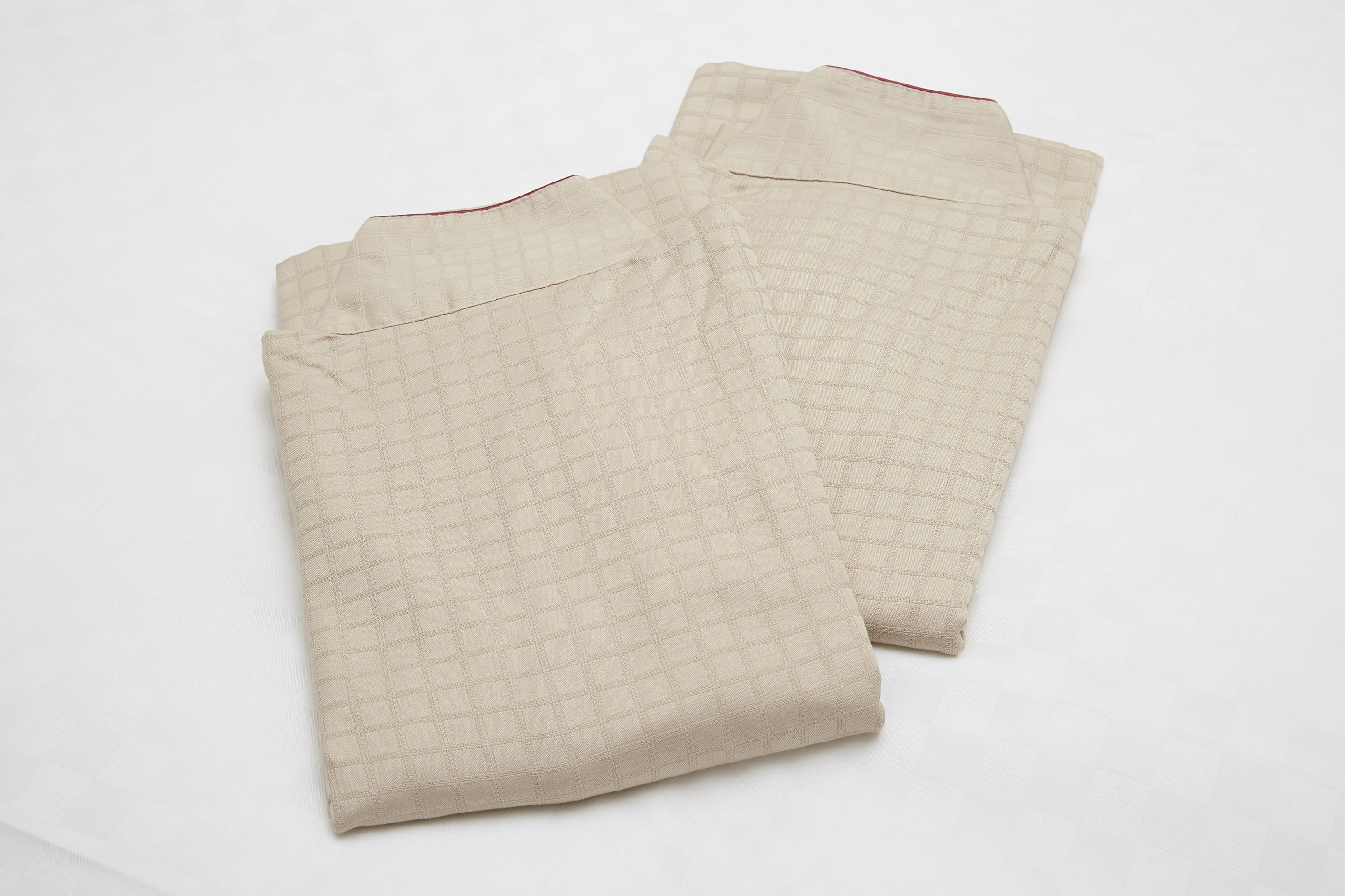 Two beige checkered pants laid out on a white surface.