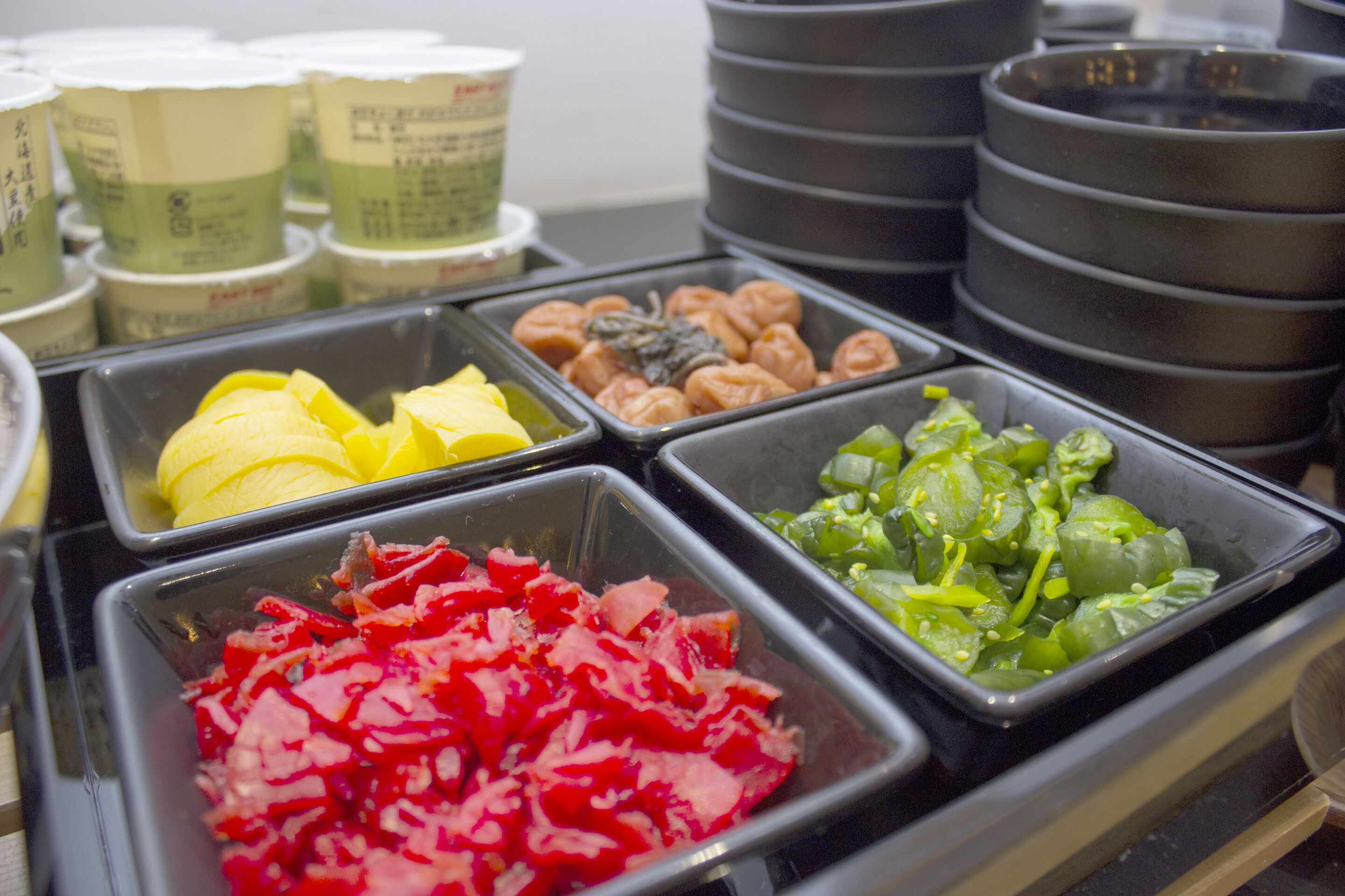 Een buffet met diverse soorten eten, waaronder plakjes banaan, rode paprika en groene groenten.