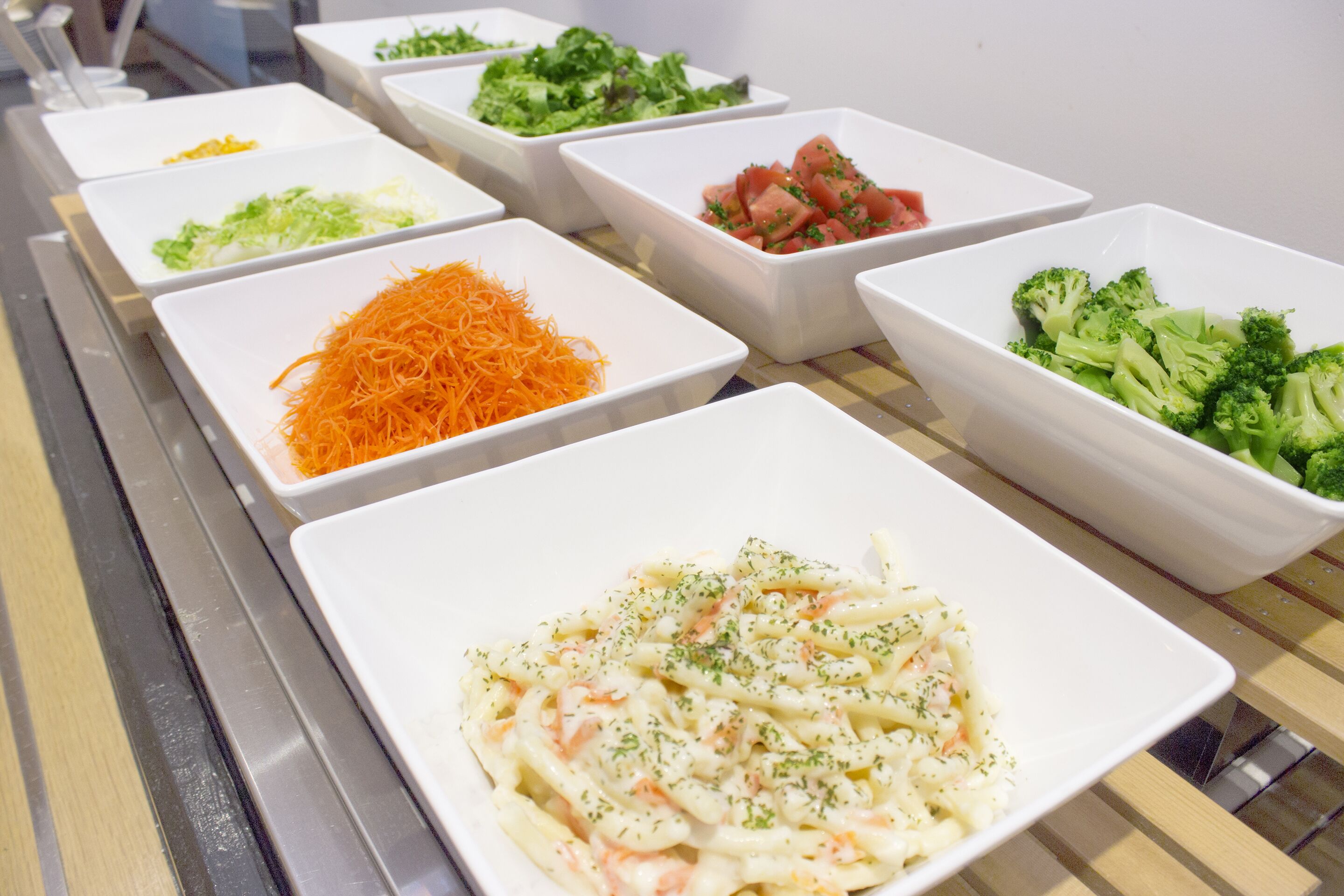 A buffet with various dishes including pasta, vegetables, and salads.