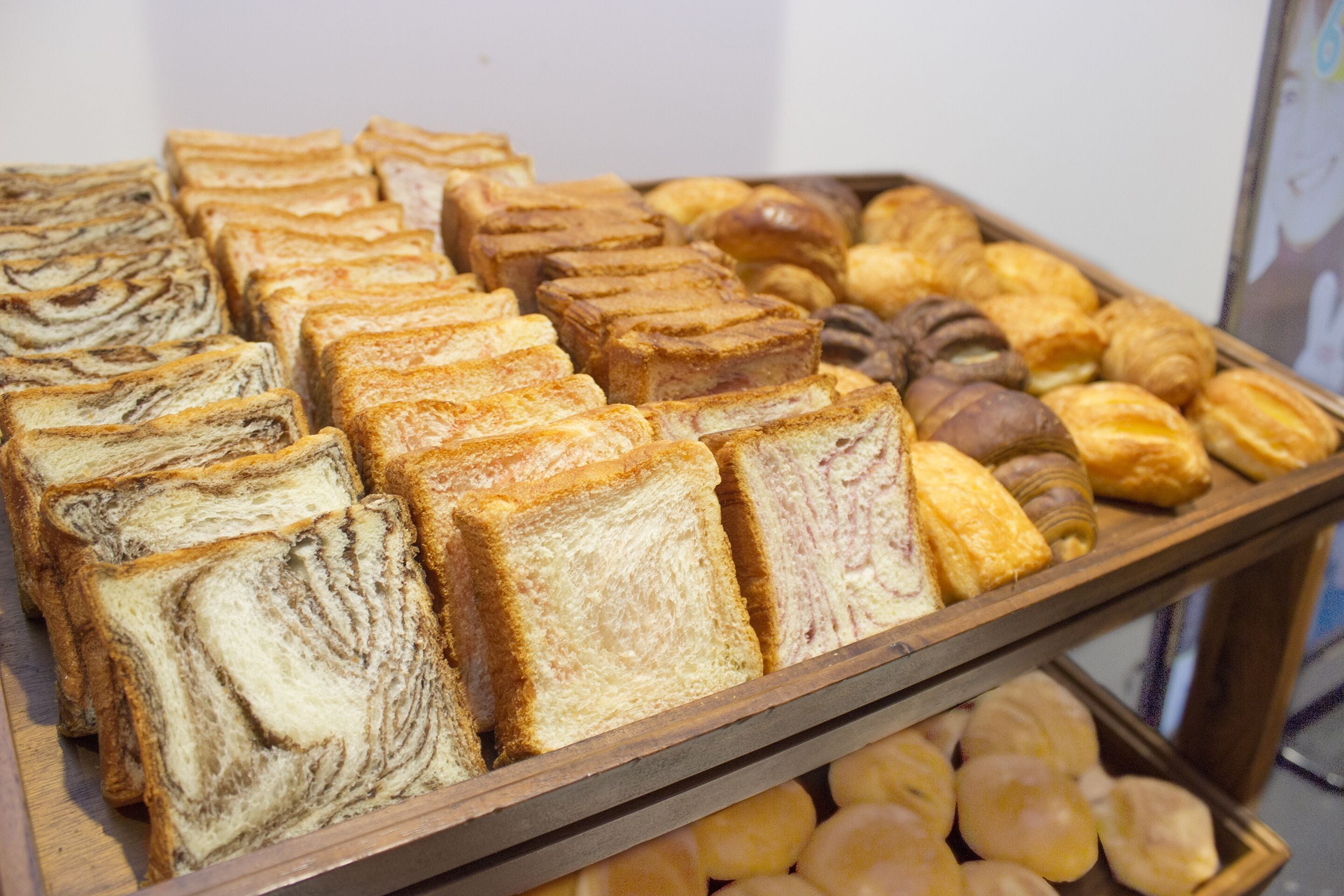 A display of various pastries and bread, including croissants, rolls, and a marble loaf.