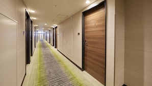 Ein Hotelgang mit Teppichmuster, Holztüren und eingelassener Beleuchtung.