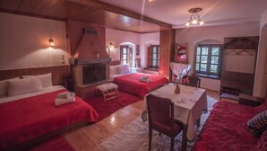 Una habitación acogedora con dos camas, una chimenea, una mesa de comedor y una ventana con vistas.