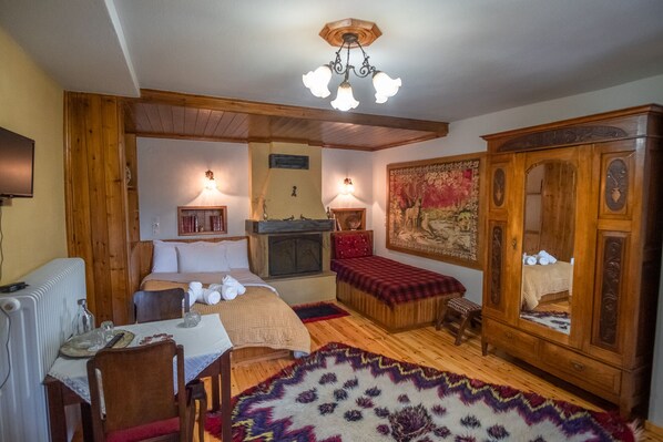 A cozy room with a bed, a wooden cabinet, a fireplace, and a rug.