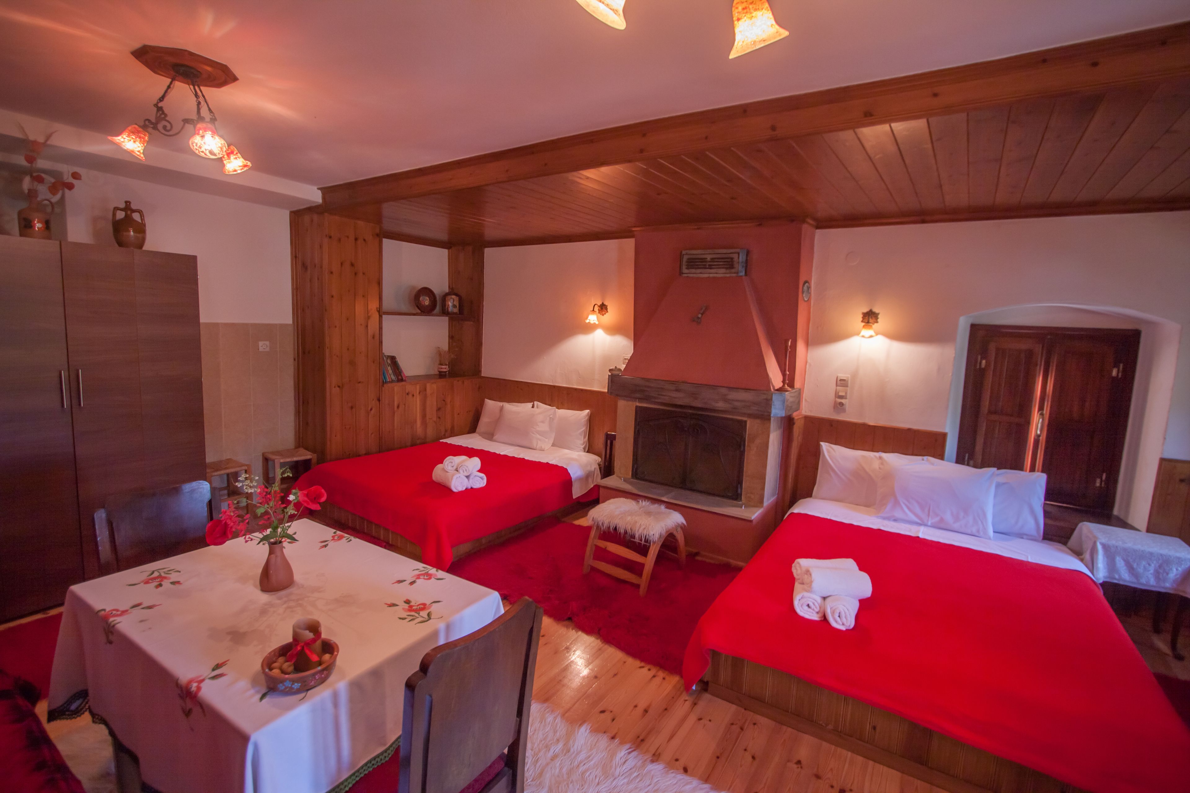 A cozy room with two beds, a dining table, and a fireplace.