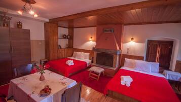 A cozy room with two beds, a dining table, and a fireplace.