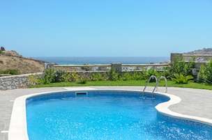 Una piscina al aire libre, sombrillas, sillones reclinables de piscina