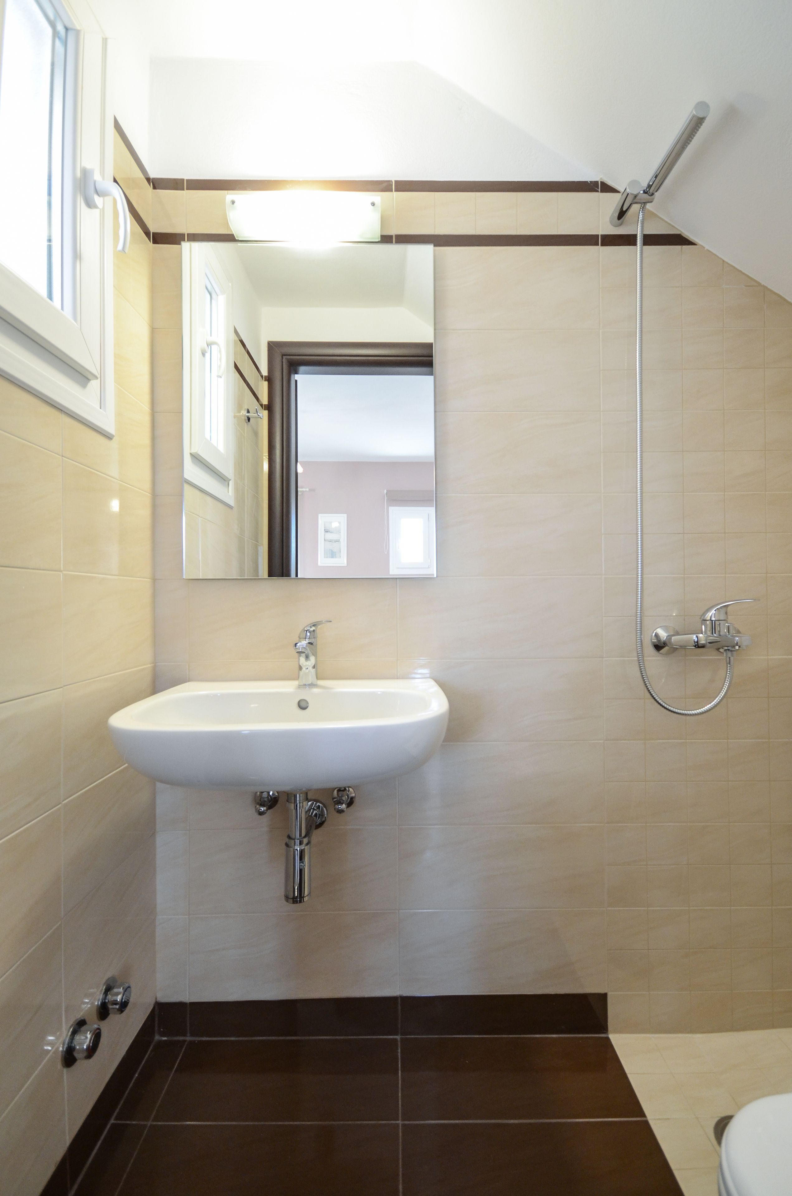 A bathroom with a sink, mirror, and shower.