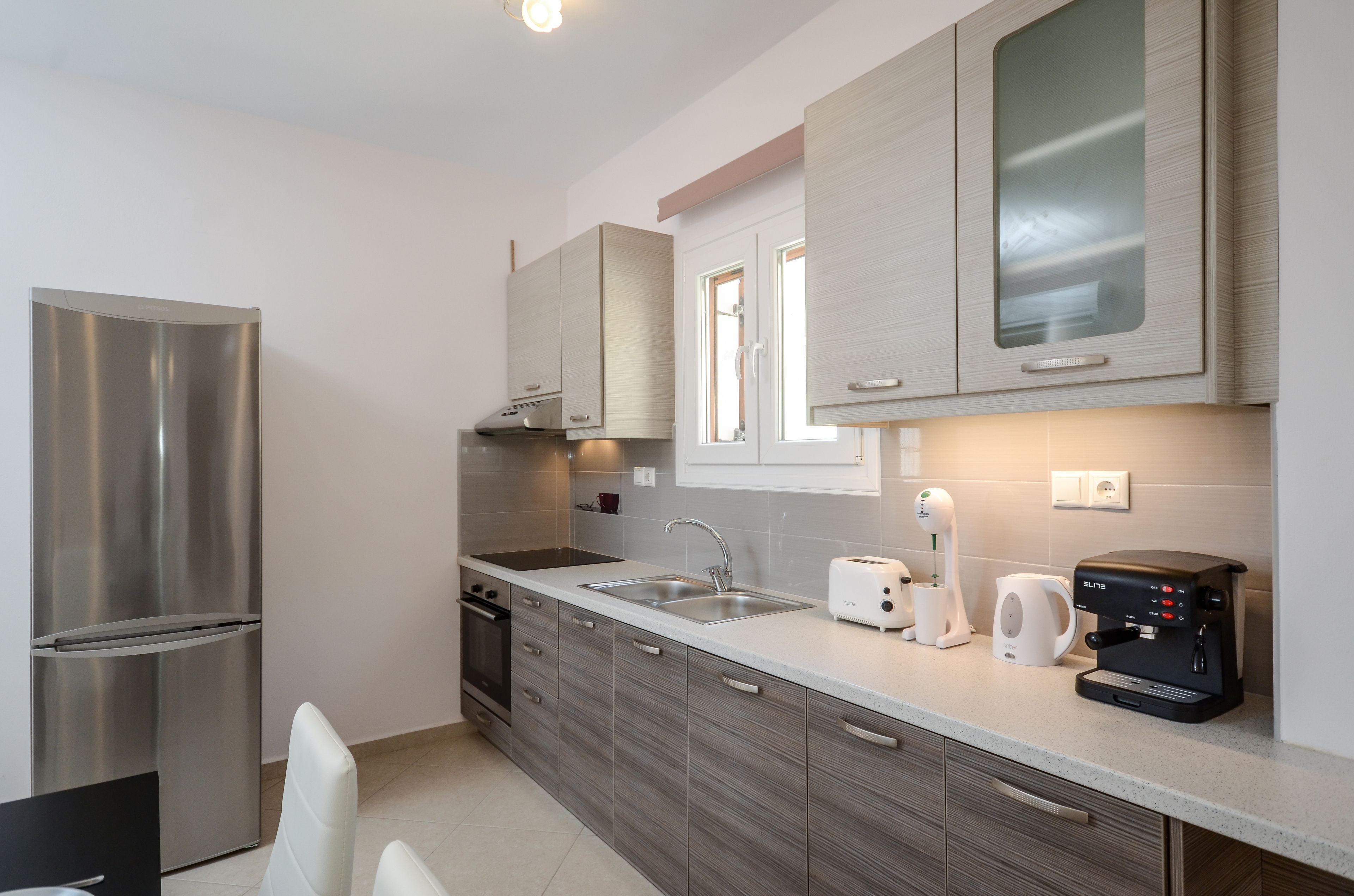 Una cucina moderna con elettrodomestici in acciaio inossidabile, forno integrato, lavello e macchina da caffè.