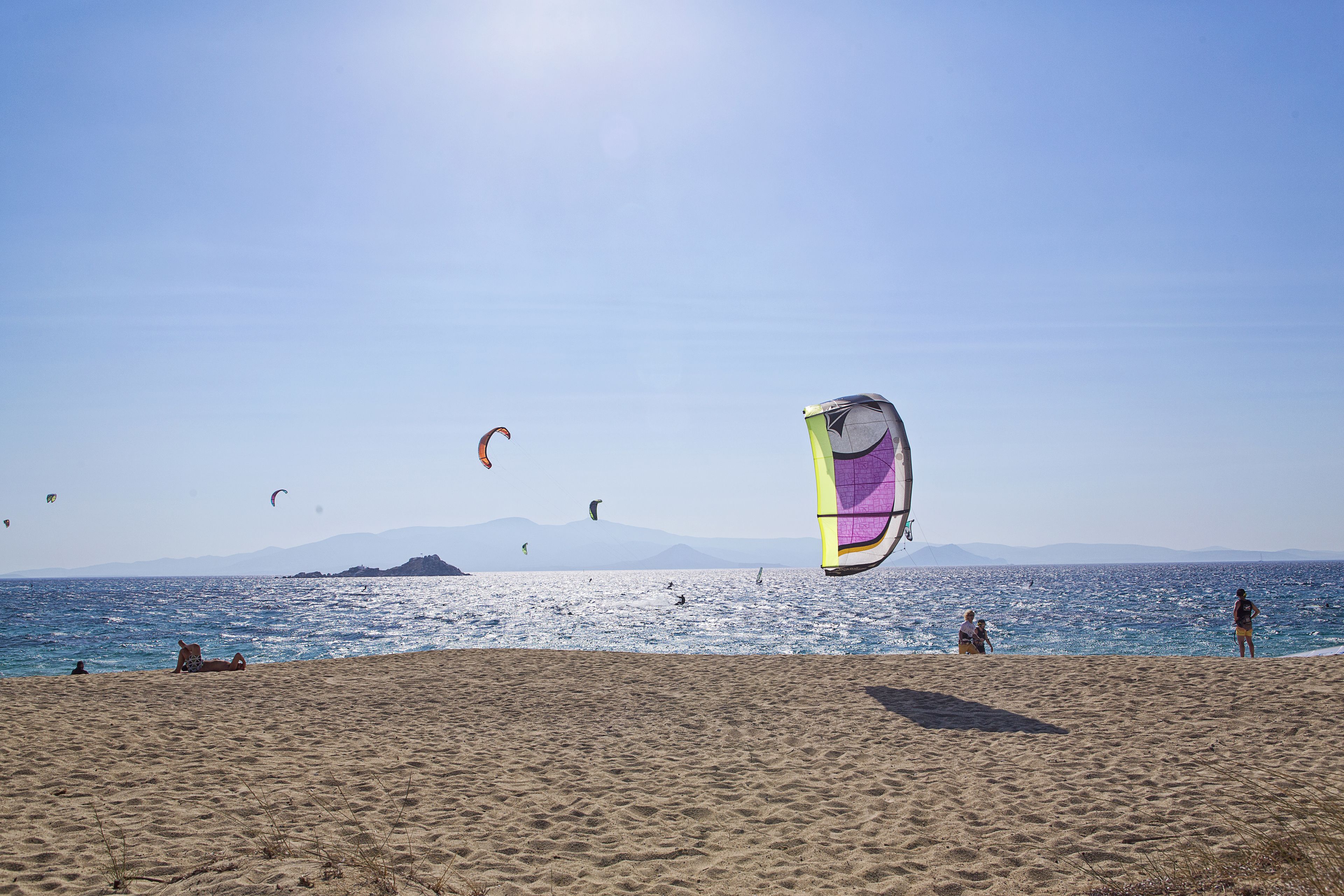 Une plage avec des gens, un cerf-volant et un ciel dégagé.