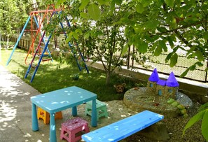 Children can play safely in this enclosed area with a swing set, slide, and playhouse.