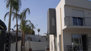Un bâtiment moderne à deux étages, doté d’un toit plat, d’un balcon à l’étage supérieur et d’une entrée sécurisée par un portail.