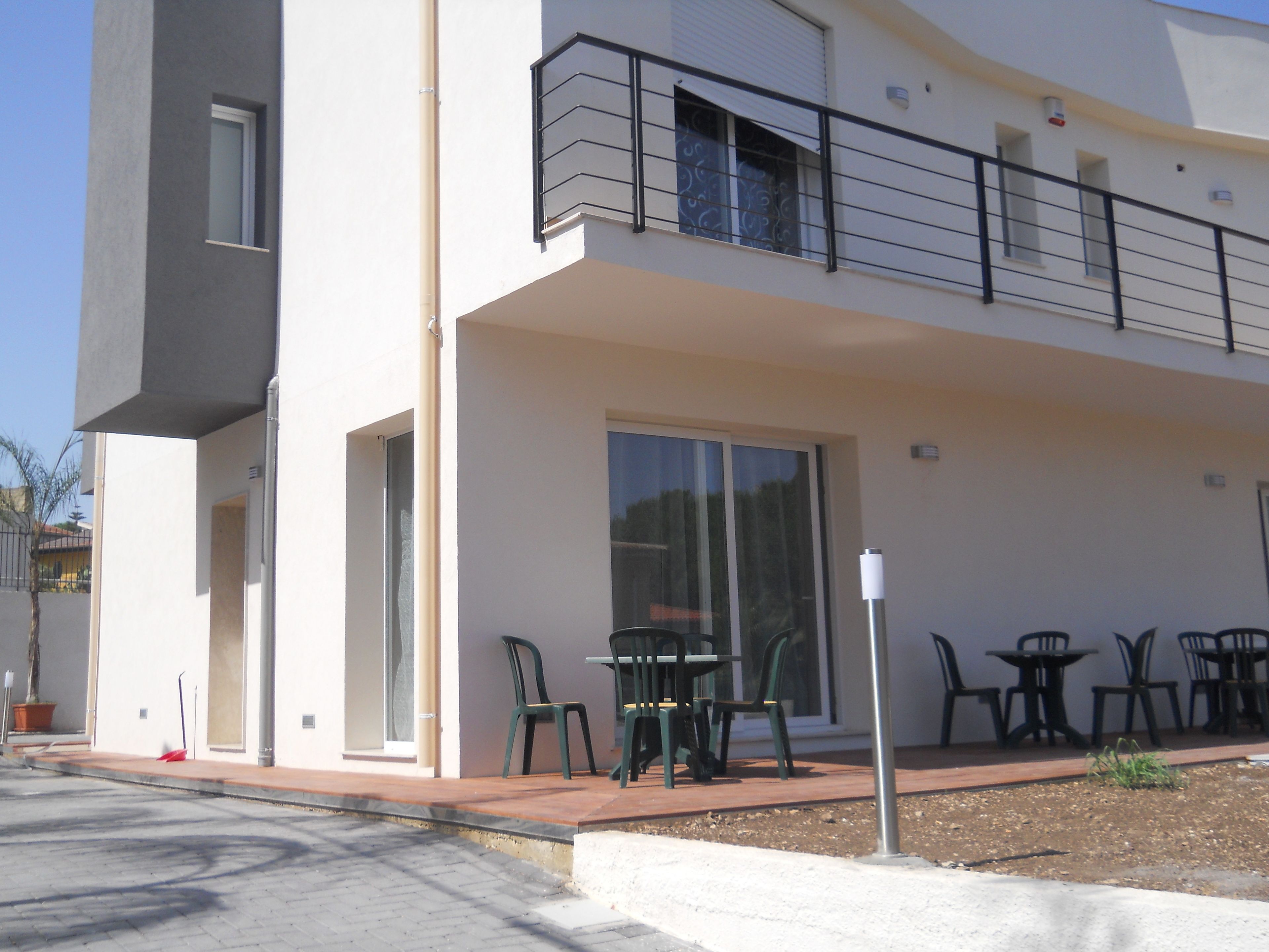 A modern building with a balcony, outdoor seating area, and a clear view of the sky.