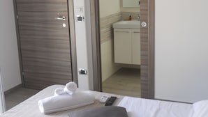 Une chambre d’hôtel avec un lit, des oreillers, une télécommande et une serviette soigneusement pliée.