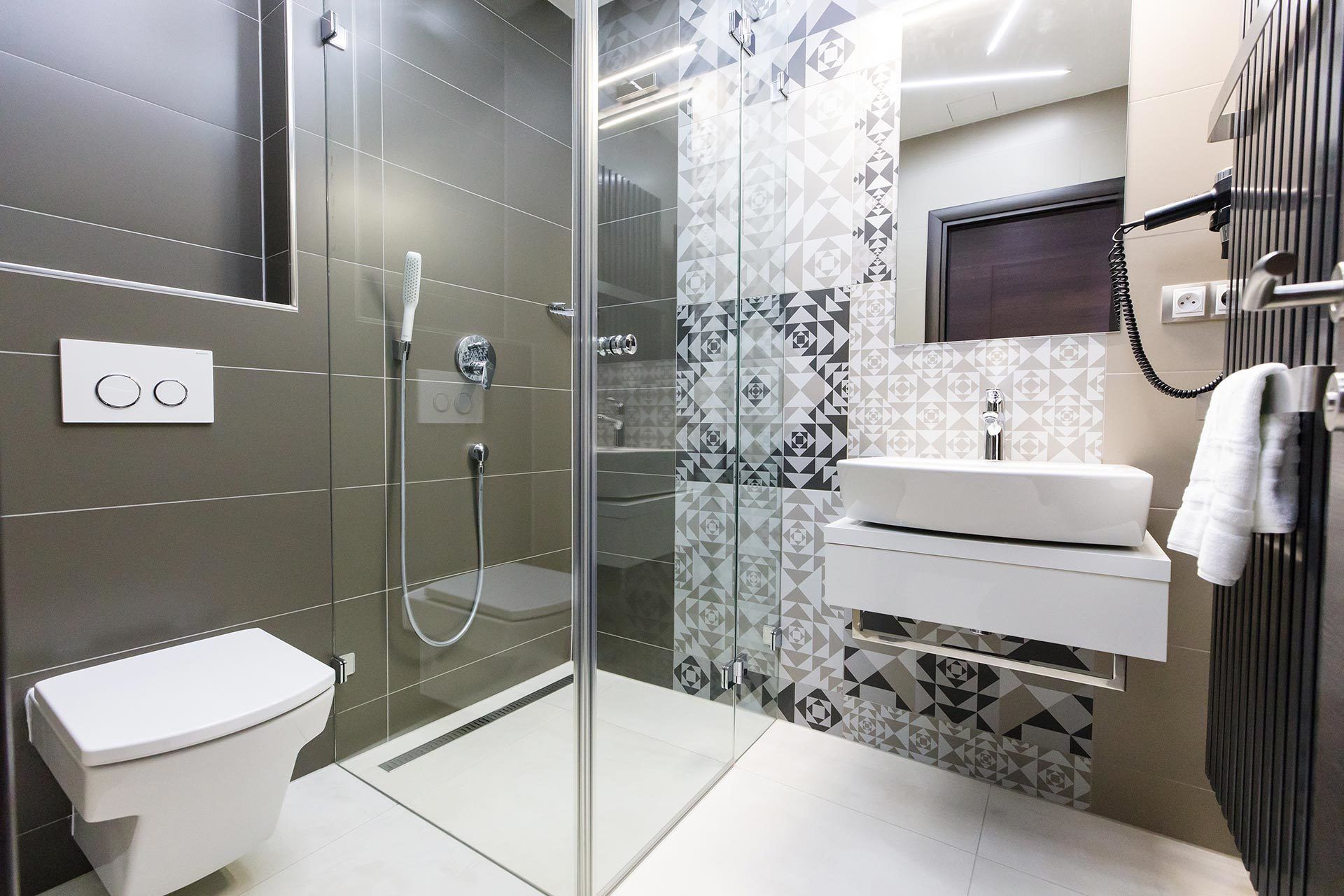 Une salle de bain moderne avec une douche à parois de verre, des toilettes et un meuble-lavabo avec un évier et un miroir.