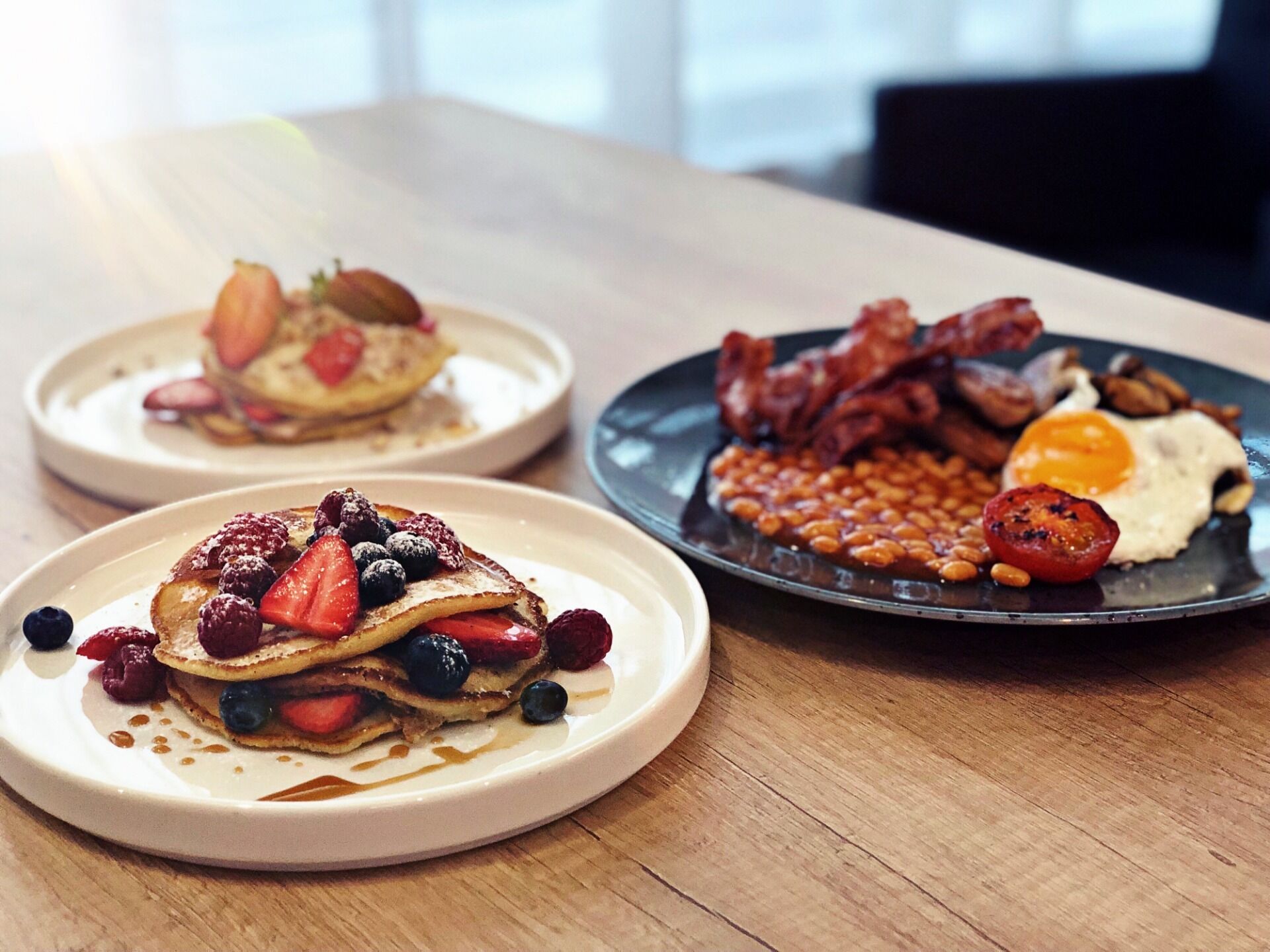 Trois assiettes de nourriture pour le petit-déjeuner sur une table en bois.