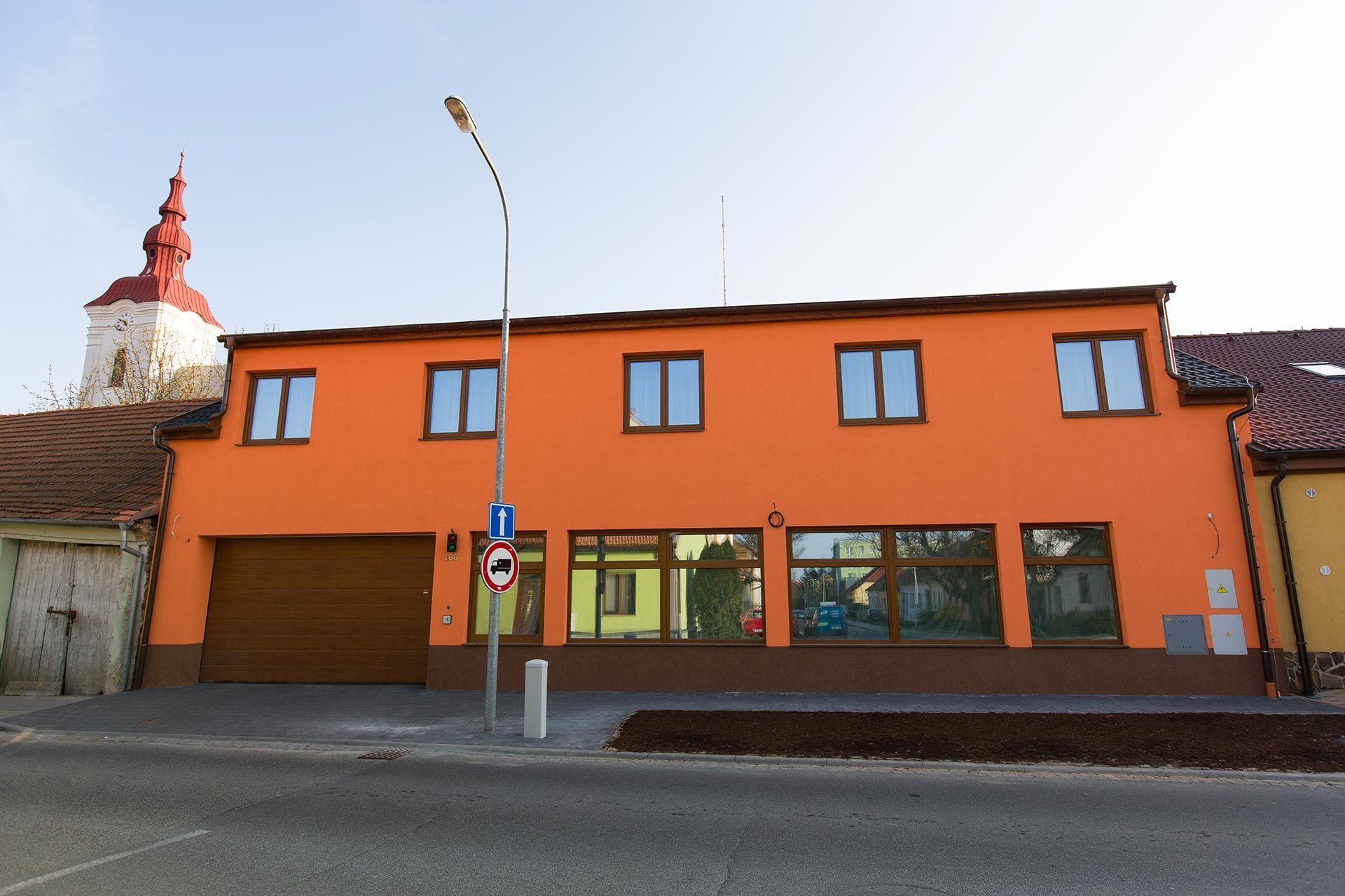 En toetagers bygning med garageport, et parkeringsforbudsskilte og en gadelampe.