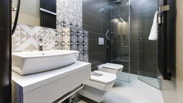 A modern bathroom with a large white sink, two toilets, and a glass-enclosed shower area.