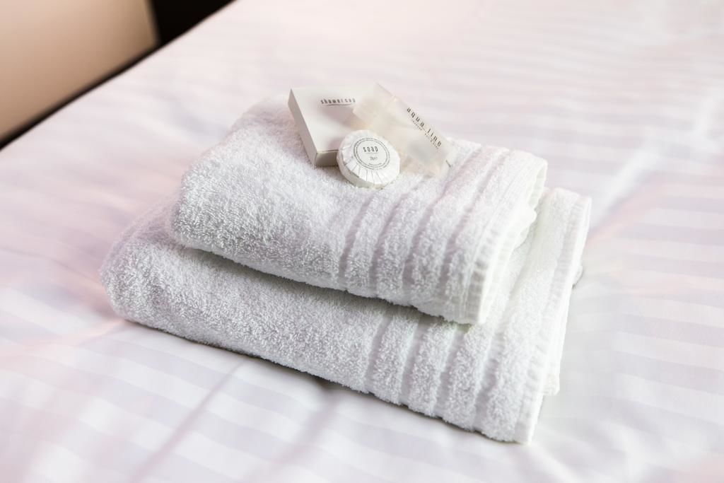 A neatly folded white towel with a tag on a bed.