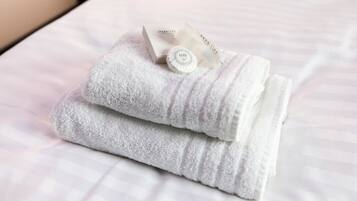 A neatly folded white towel with a tag on a bed.
