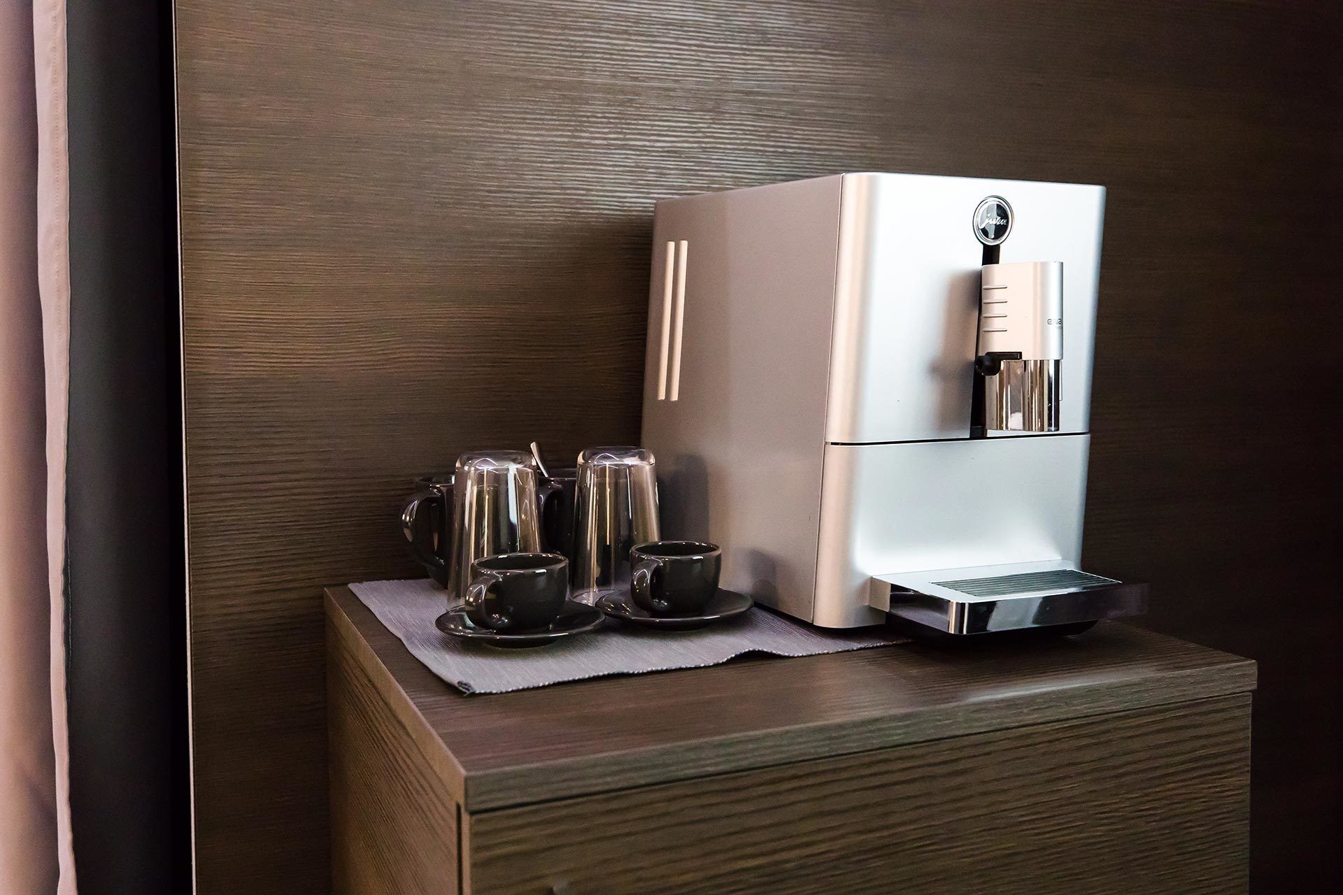 Eine moderne Küche mit einer integrierten Espressomaschine, einer Kaffeemaschine und einem Wasserkocher auf einer Holzausziehtafel.