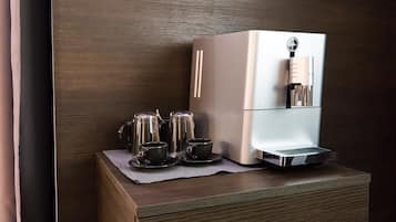 A modern kitchen with a built-in espresso machine, a coffee maker, and a tea kettle on a wooden countertop.